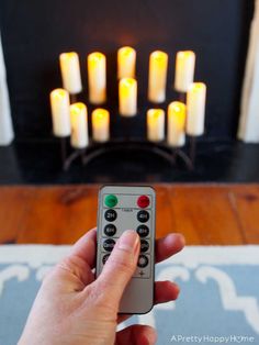 a person holding a remote control in front of a fireplace with lit candles on it