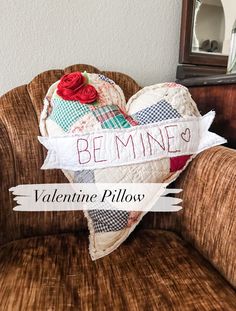 a heart shaped pillow sitting on top of a chair with the words be mine written on it