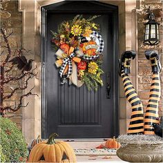 a front door decorated for halloween with pumpkins and sunflowers