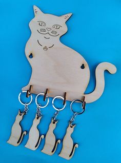 a wooden cat key holder with five cats hanging from it's hooks on a blue background