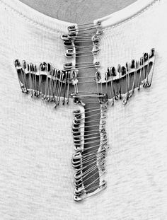 a man wearing a white t - shirt has a cross made out of metal pins