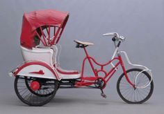 an old fashioned tricycle with a red cover on the back