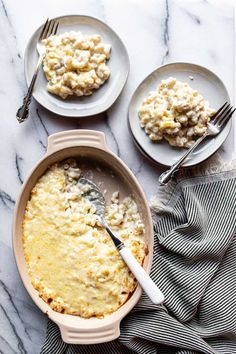 two plates with food on them next to a bowl of macaroni and cheese