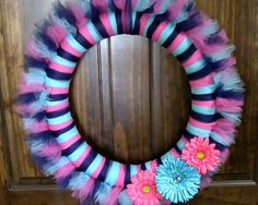 a wreath with pink, blue and black feathers