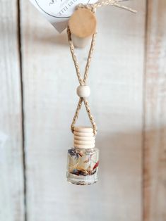 a glass jar hanging from a rope with a tag attached to it and a wooden bead