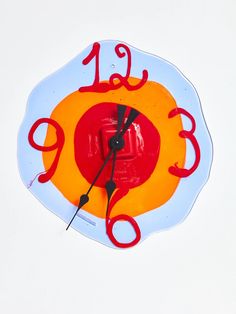 a glass clock with red numbers on the face and hands, painted in bright colors