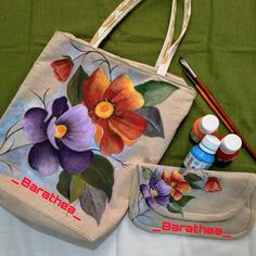 two bags with flowers painted on them next to some paintbrushes and an artist's palette