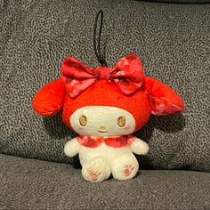 a hello kitty stuffed animal with a bow on its head sitting on a gray couch