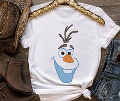 a t - shirt with an image of the character frozen queen on it, next to jeans