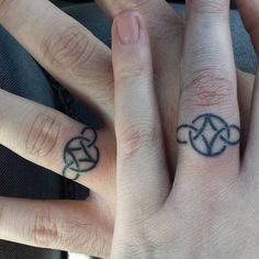 two people with matching rings on their fingers, one has a heart and the other has a cross