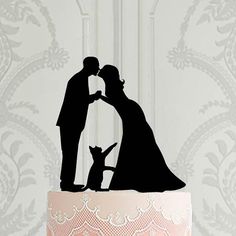 a wedding cake topper with a silhouette of a bride and groom kissing in front of a cat