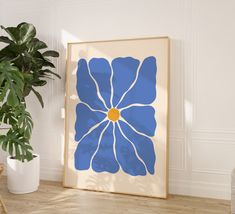 a blue and white flower is on the wall next to a potted plant