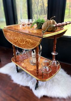 a wooden serving cart with wine glasses on it