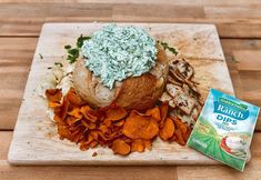 a bagel with spinach dips and sweet potato chips on a cutting board