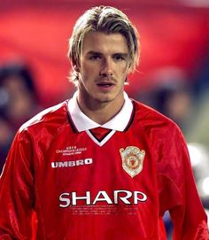 a young man in a red uniform standing on a soccer field