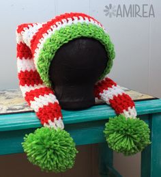 a knitted hat with pom - poms on top of a table