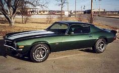 a green muscle car parked in a parking lot