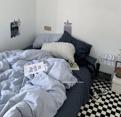 an unmade bed in a white room with black and white checkered flooring