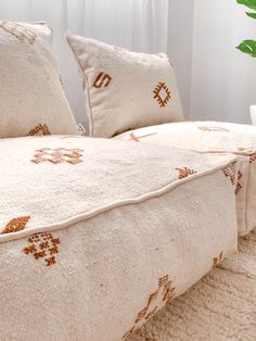 a bed with two pillows on it next to a potted plant and white curtains