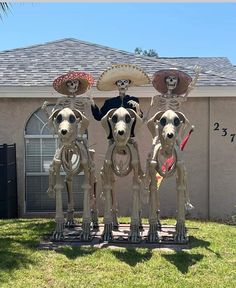 three statues of dogs with sombreros on their heads in front of a house