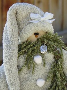 a stuffed animal with a white hat and scarf around it's neck is covered in green moss