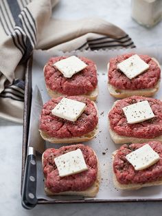 mini hamburgers with cheese on top are sitting on a baking sheet next to a glass of milk