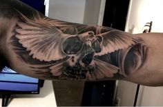 a man's arm with a bird and skull tattoo on it