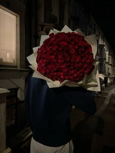 a person with a bunch of red roses on their head in front of a building