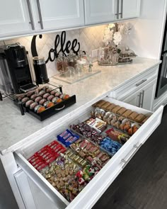 an open drawer in the middle of a kitchen counter filled with snacks and coffee items