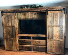 an entertainment center made out of wood with sliding doors on each side and a flat screen tv mounted to the wall