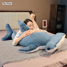 a woman laying on top of a blue shark pillow