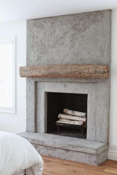 a bedroom with a stone fireplace in the corner and wood logs on the mantel