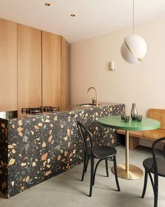 a table and chairs in a room with wooden cabinets on the wall, and a green counter top