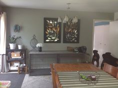 a dining room table with chairs and two paintings on the wall