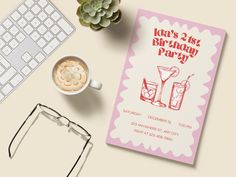 a pink birthday party card next to a keyboard, glasses and cup of coffee on a desk