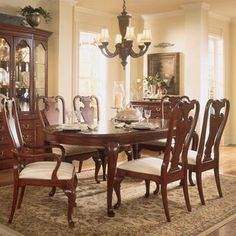 a dining room table with chairs and a china cabinet in the corner next to it