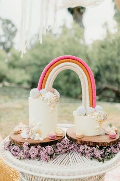 two cakes with rainbow decorations on top of each one sitting in front of a cake stand