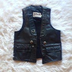 Vtg Black Schott Nyc/Harley Davidson Western Biker Leather Vest Mens Size Small Has Large Trademark Harley Davidson Eagle Patch On The Back, Silver Harley Eagle Pin And Western Style Buttons, Fringe Details, Two Pockets, And Leather Double Cylinder Shape Clasp In Good Preowned Condition- Some White Spots On Interior Of Vest, And Seams Are A Bit Ripped On Right Side Interior Of Vest, But No Other Discernible Flaws - From A Smoke Free Home Measurements Laid Flat: Length: 23" Chest: 18" 2024 Fitted Biker Jacket With Button Closure, Classic Fitted Vest For Biker Events, Vintage Winter Biker Jacket With Snap Buttons, Vintage Biker Jacket With Snap Buttons For Winter, Vintage Black Biker Jacket With Pockets, Black Vintage Biker Jacket With Pockets, Vintage Black Vest For Streetwear, Vintage Black Vest For Fall, Black Vintage Vest For Fall