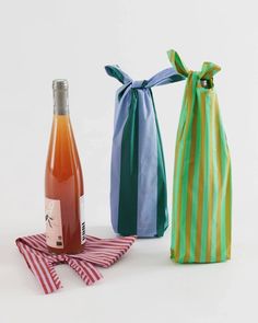 two bottles of wine are sitting next to each other on a cloth bag and one bottle is empty