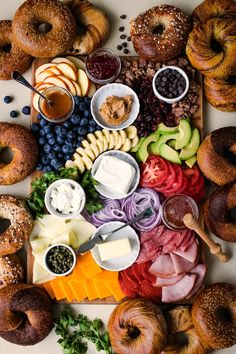 an assortment of different types of food on a cutting board with cheese, fruit and bread