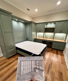 a bedroom with green cabinets and a white bed in the middle is being held up by someone's hand