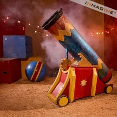 a small toy train with a large cannon on it's back in the sand