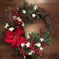 a christmas wreath with poinsettis, cotton balls and greenery on a wooden floor