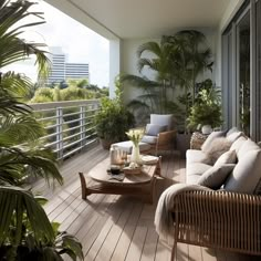 a balcony with wicker furniture and potted plants on the side wall, along with wooden flooring