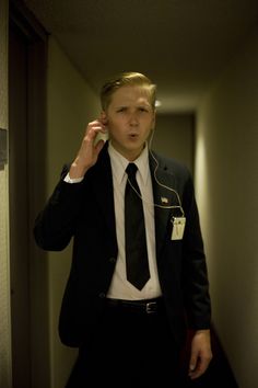 a man in a suit and tie is listening to headphones while walking down a hallway