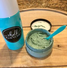 a blue cup filled with green cream next to a container of whipped cream on a wooden tray