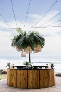 an outdoor hot tub next to the ocean with palm trees on top and lights strung from above