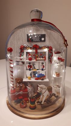 a glass case with christmas decorations and toys in it's display area on top of a table