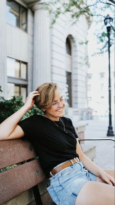 a woman sitting on top of a wooden bench