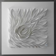 an intricate white paper sculpture is displayed on the wall in front of a gray background